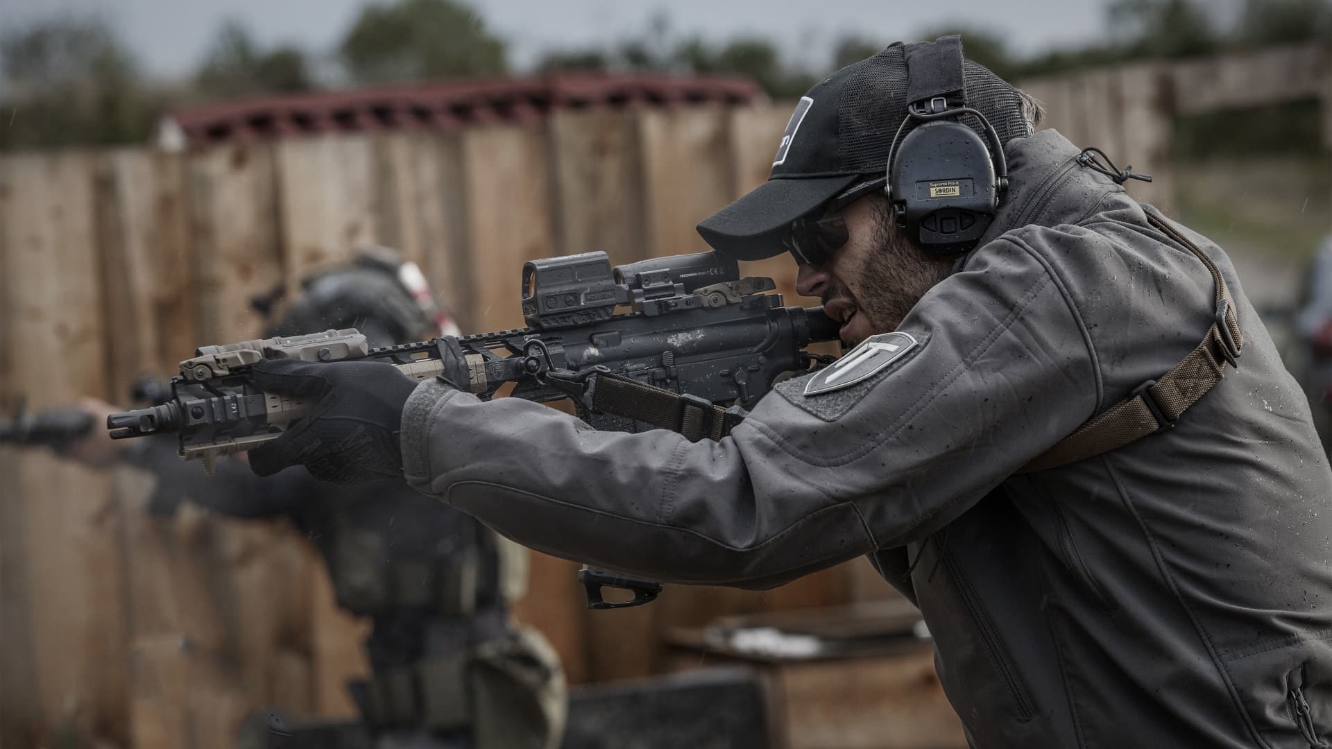 Man aiming rifle furnished with a Holosun Red Dot